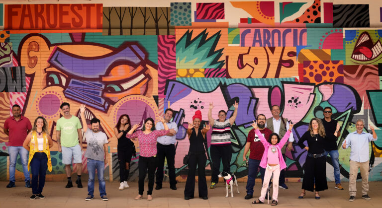 Foto com a equipe de produção do Território Criativo em frente a uma parede com grafite.